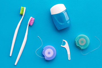 Tooth care with toothbrush, dental floss and dentist instruments. Set of cleaning products for teeth on blue background top view