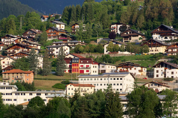 Naklejka premium Domegio di Cadore, Italy August 11, 2018: Beautiful buildings in a mountain village at sunrise.
