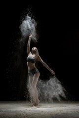 Fototapeta na wymiar Girl in lingerie dancing in the dust in the dark