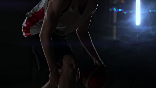 one young adult man, basketball player dribble ball, dark indoors basketball court. Slow motion