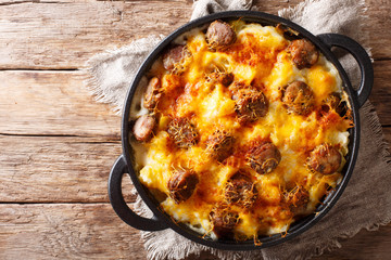Delicious potato casserole, sausages with cheese sauce close-up in a frying pan. horizontal top view