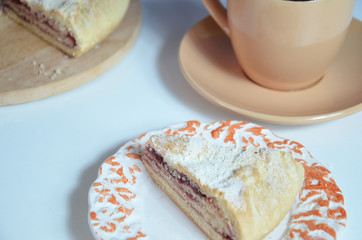 Homemade pie with cherry berries, cup of tea and fork on white wooden table. Top view.