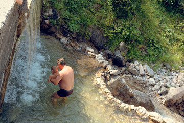 man bathes in a mountain stream falls on the stones in nature.