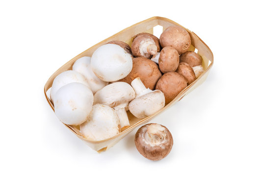 Cultivated raw white and brown mushrooms in the wooden basket