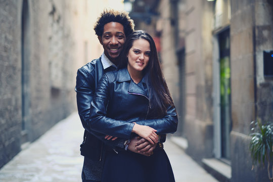 Una pareja feliz y enamorada interracial en las calles de Barcelona pasando un d&iacute;a bonito.