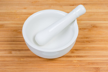Porcelain kitchen mortar and pestle on a wooden cutting board