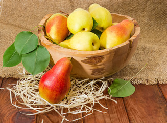 Red and yellow pears in vintage wooden fruit bowl