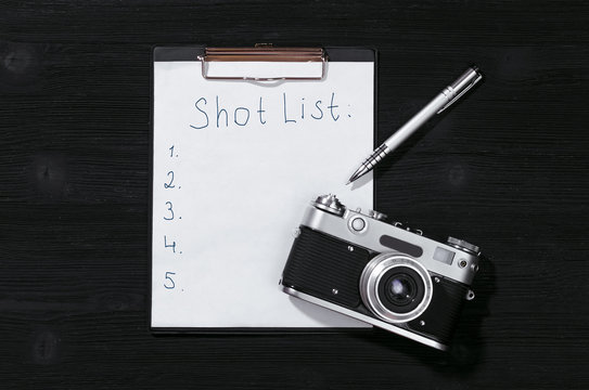 Shot list mockup. Vintage film photo camera paper page on black wooden table background.