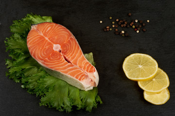 Raw salmon steak and spices on slate plate ready for cooking.