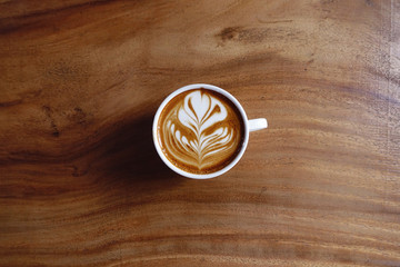 a cup of latte art coffee on wooden background