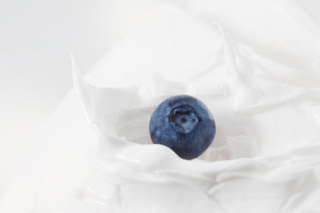 Sweet blueberry in yogurt. Close-up milk or cheese dessert with raspberry. 