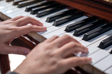 Obraz premium Closeup image of hands playing a vintage wooden grand piano