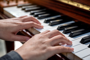Fototapeta premium Closeup image of hands playing a vintage wooden grand piano