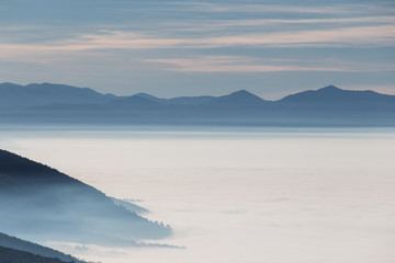 Fog filling a valley in Umbria (Italy), with layers of mountains and hills and various shades of blue