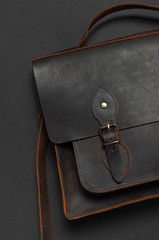 Fashionable concept. Brown leather men's bag on black background top view flat lay with copy space....