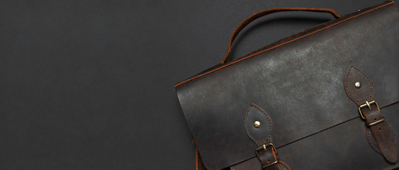Fashionable concept. Brown leather men's bag on black background top view flat lay with copy space....