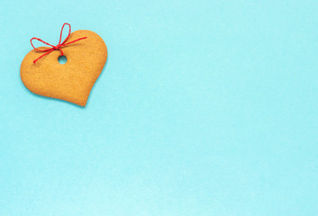 Ginger cookies heart-shaped decorated with a bow on a blue background. Top view Copy space Valentine card