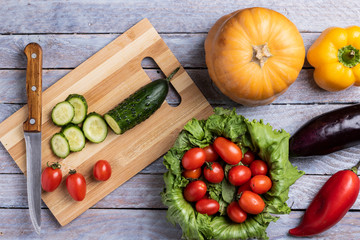 cucumbers, salad leaves and tomatoes cherry on grey wooden table