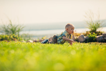Naklejka na ściany i meble Baby boy on green grass nature background