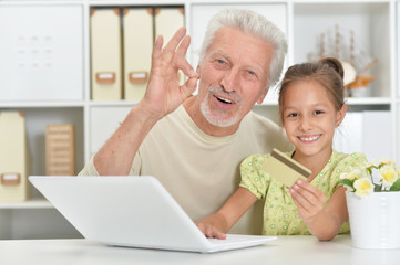 Portrait of grandfather and granddaughter using laptop together