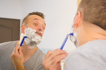 Guy shaving his beard in bathroom