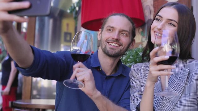 Happy Couple With Wine Taking Photos On Phone At Restaurant