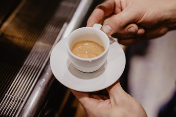 Hands of young man barista holding a cup of coffee in a cafe.