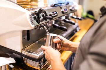 Cropped image of barista steaming milk in coffeeshop