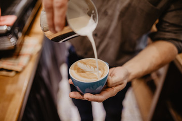 Man hands pouring milk into coffee making espresso.