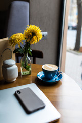 Coffee shop desk table with smartphone, laptop computer and cup of coffee. Top view with copy space, flat lay.