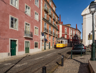 Fototapeta na wymiar Lisbon - Portugal. The famous yellow tram runs through the streets of the historic Alfama district