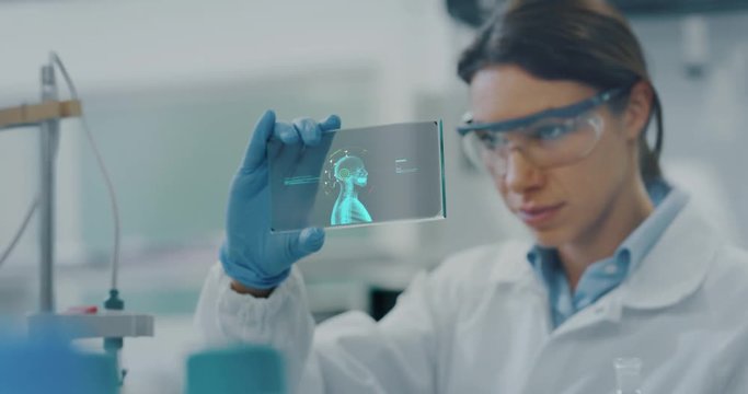 Portrait of futuristic researcher using the augmented reality screen with hologram graphics for viewing results of his research in laboratory. Shot in 8K. Concept of futuristic medicine and science