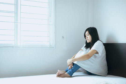 Unexpected pregnancy concept,Asian woman sitting on bedroom at home,Female feeling unhappy and confused problem family