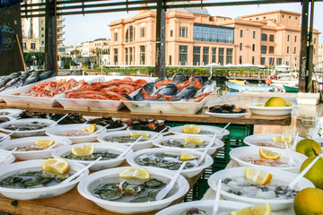 Open air street food fish market with raw fresh sushi ready to eat: shrimp, oyster, sea urchin,...