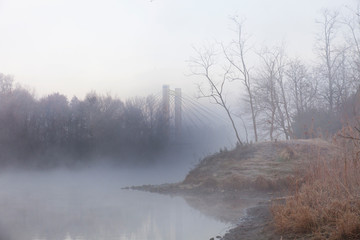 un pilastro di un ponte avvolto dalla nebbia invernale - 240350026