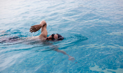 Professional male watersport ,which Slim sportsman swimming in a pool.,evening scene.