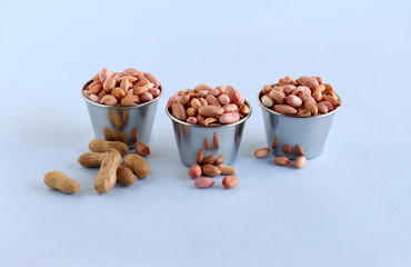 Raw peanut or groundnut, which is a healthy food, rich in fiber and protein, in steel cups, and...