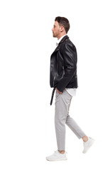 Side view of going  handsome man in a leather jacket and trouser