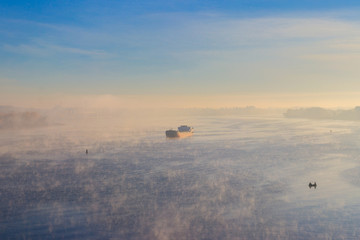 Industrial ship sailing down the river in the mist at morning