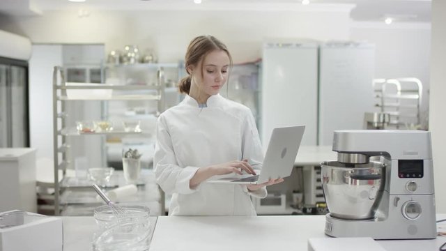Yoгтп head cook in professional uniform is using her laptop