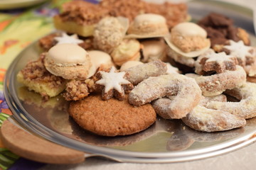 Platte mit Weihnachtsplätzchen über einer gedeckten Kaffeetafel - Woman hands hold a plate with Christmas cookies over a muted coffee table