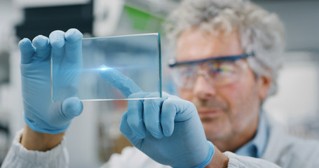 Portrait of futuristic researcher using the augmented reality screen with hologram graphics for viewing results of his research in laboratory. Shot in 8K. Concept of futuristic medicine and science