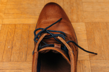 close up of old brown leather shoe on wooden background