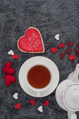 Romantic Valentine's Day breakfast. Heart-shaped cookie and a cup of tea on a gray table. Top view