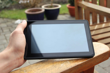 big tablet held in hand in a garden environment