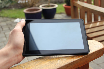 big tablet held in hand in a garden environment © h3design