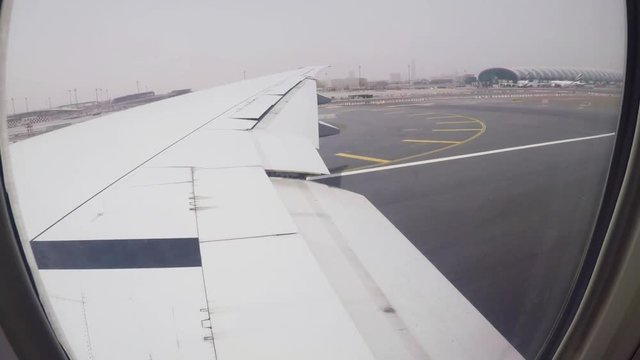 Runway from a plane window and plane s taking off at Dubai airport.