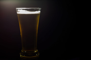 Cold beer in a glass on a dark background