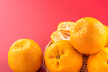 Beautiful and delicous tangerine isolated on red background with bamboo sieve, new modern auspicious and jubilant concept of chinese new year, close up, copy space