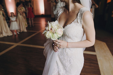 Gorgeous bride holding stylish bouquet and preparing to throw him to girls at wedding reception in...